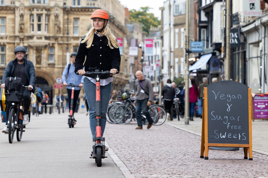 Woman riding e-scooter through high street