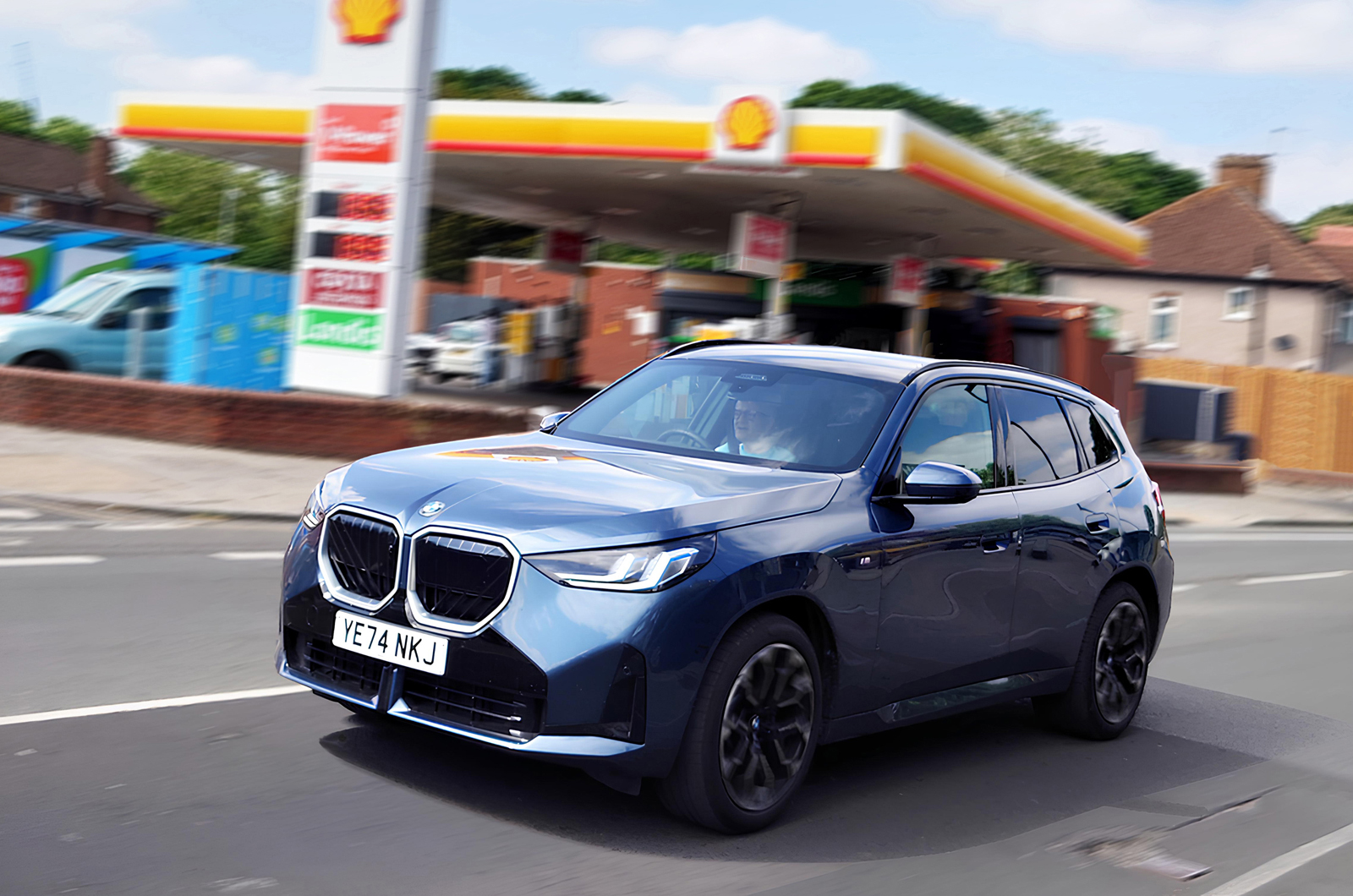 BMW X3 LT driving past petrol station
