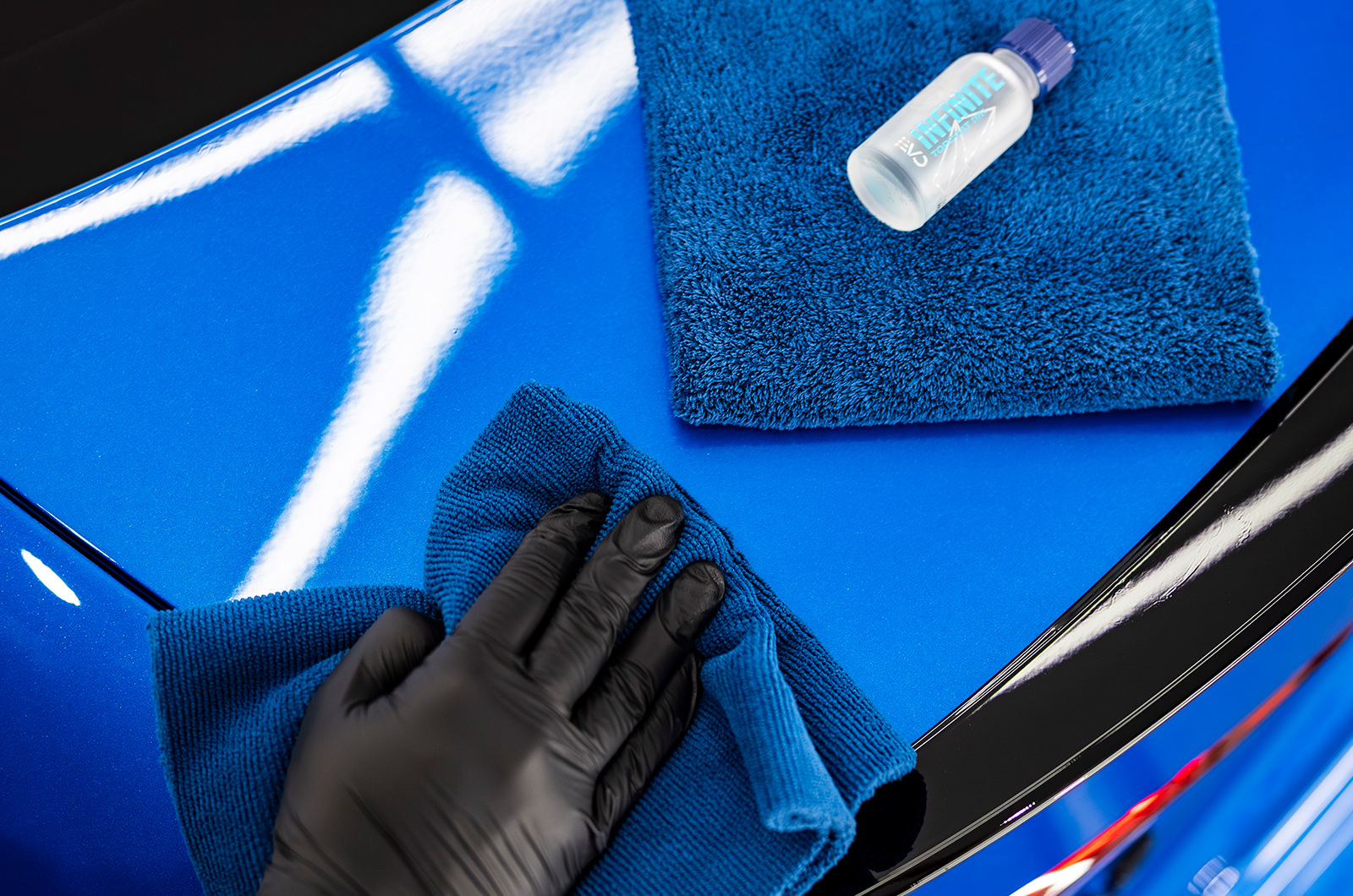 A technician polishes a blue car using Gyeon's Infinite products
