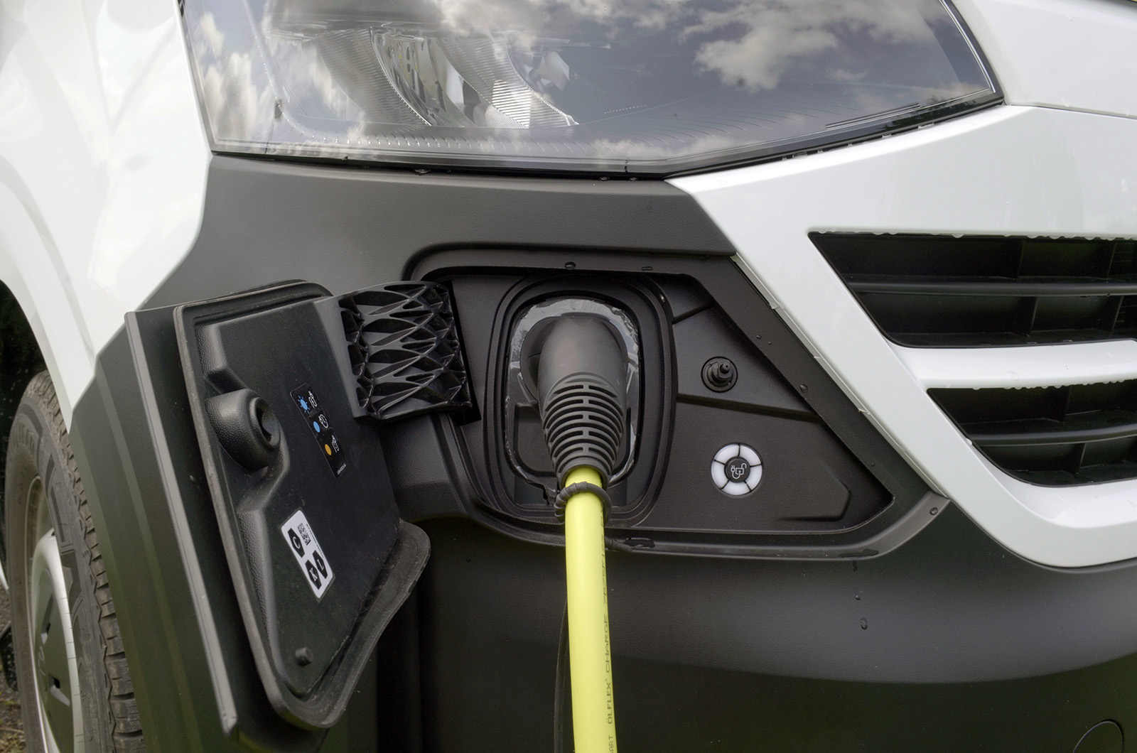 A close up shot of the Volkswagen e-Transporter's charging port with a charging cable plugged in.