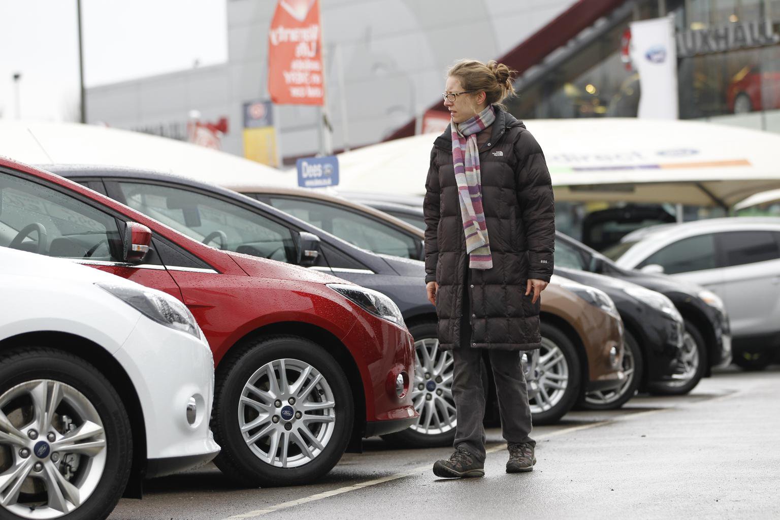 A customer browses approved used models on a car dealership forecourt
