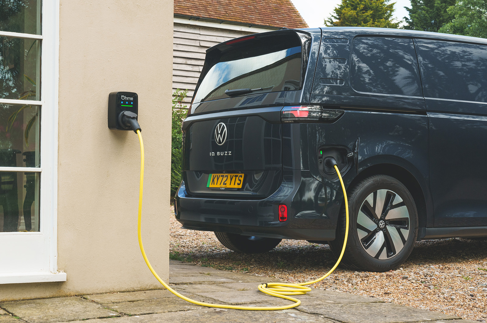 A dark blue Volkswagen ID. Buzz Cargo van is charging  outside a house
