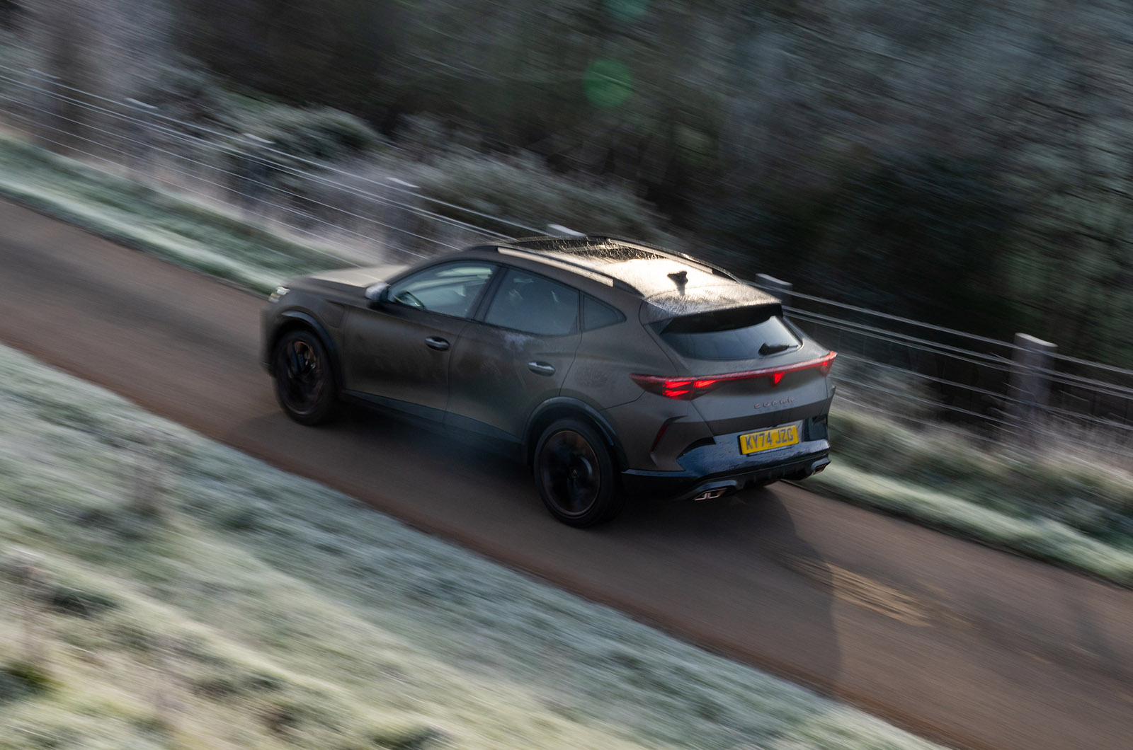 A CUPRA Tavascan e-HYBRID driving down a country road viewed from above