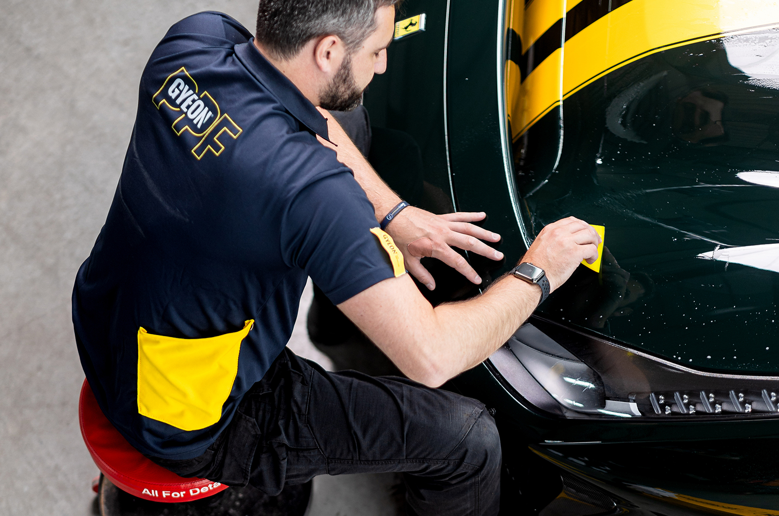 A gyeon technician applies a protective paint film (PPF)
