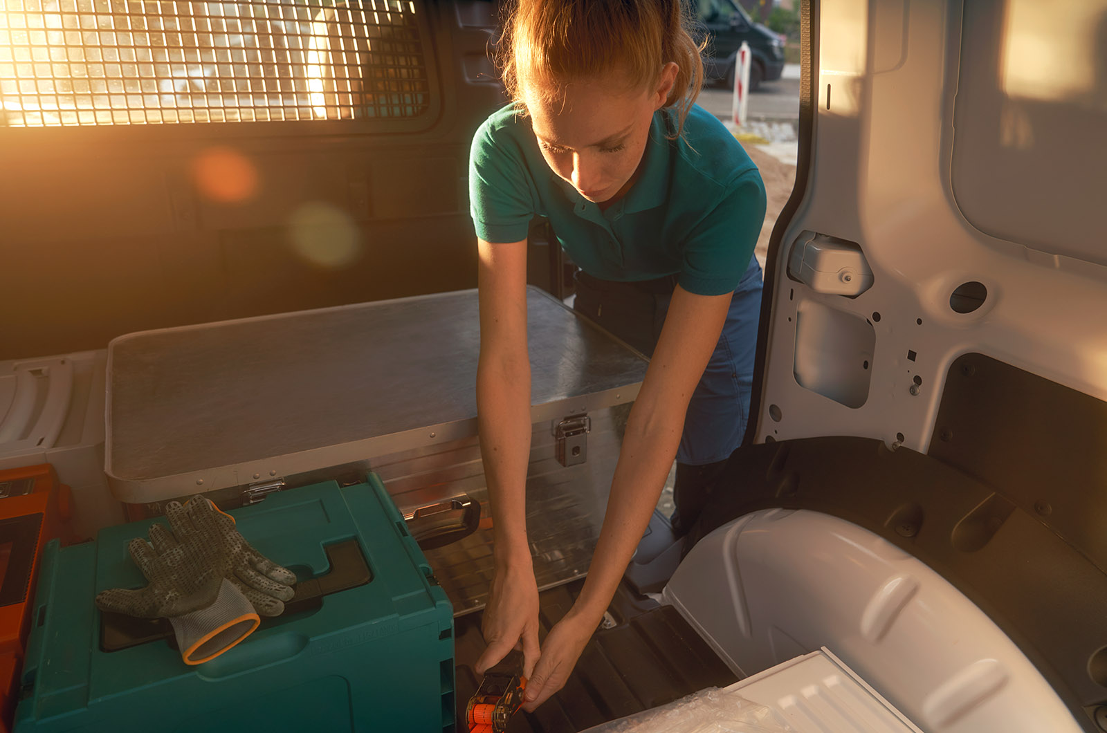A woman adjusts the loading straps in the rear of a Volkswagen Caddy Cargo