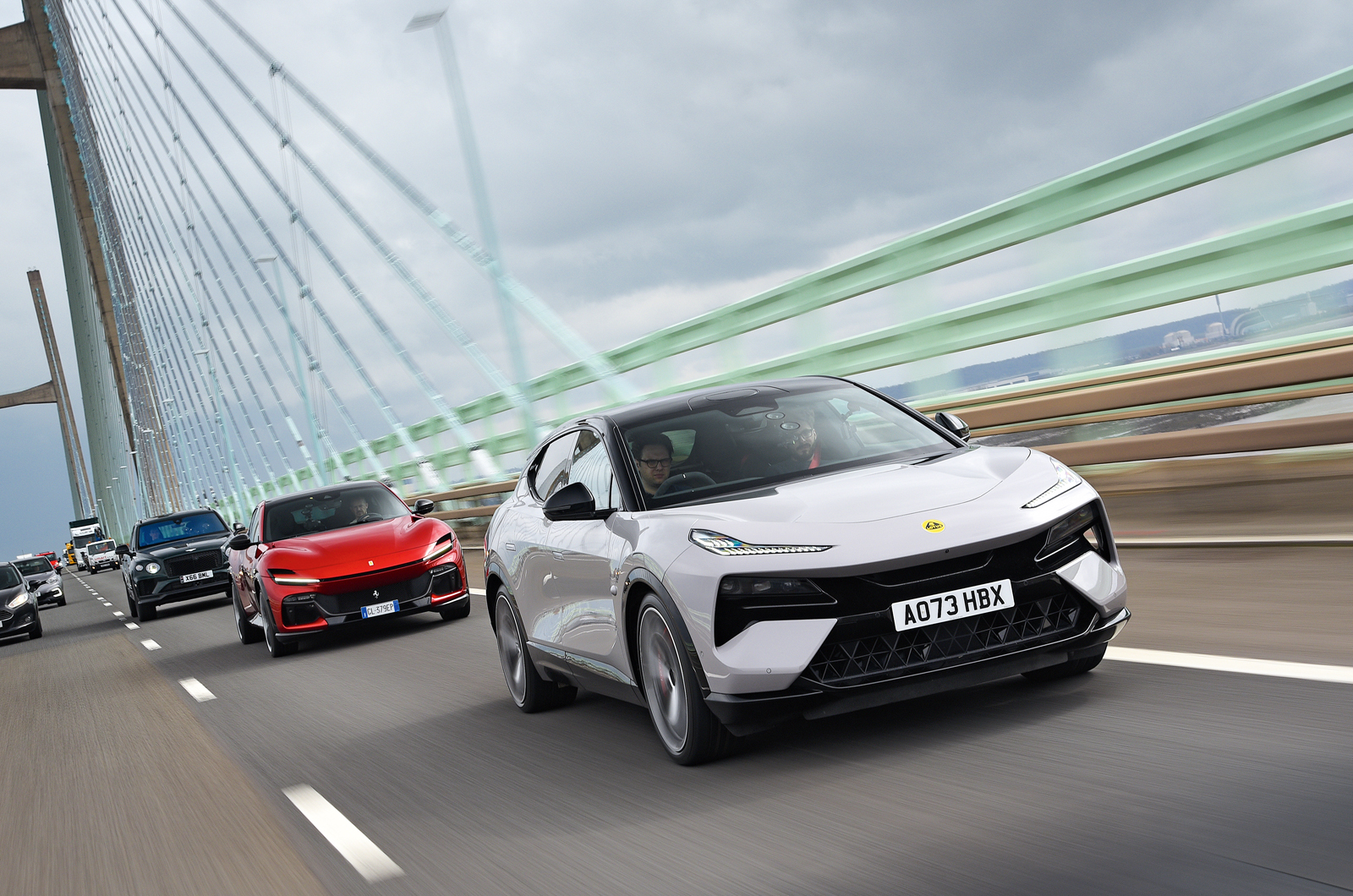 Lotus Eletre leading Ferrari Purosangue and Bentley Bentayga across Severn Bridge