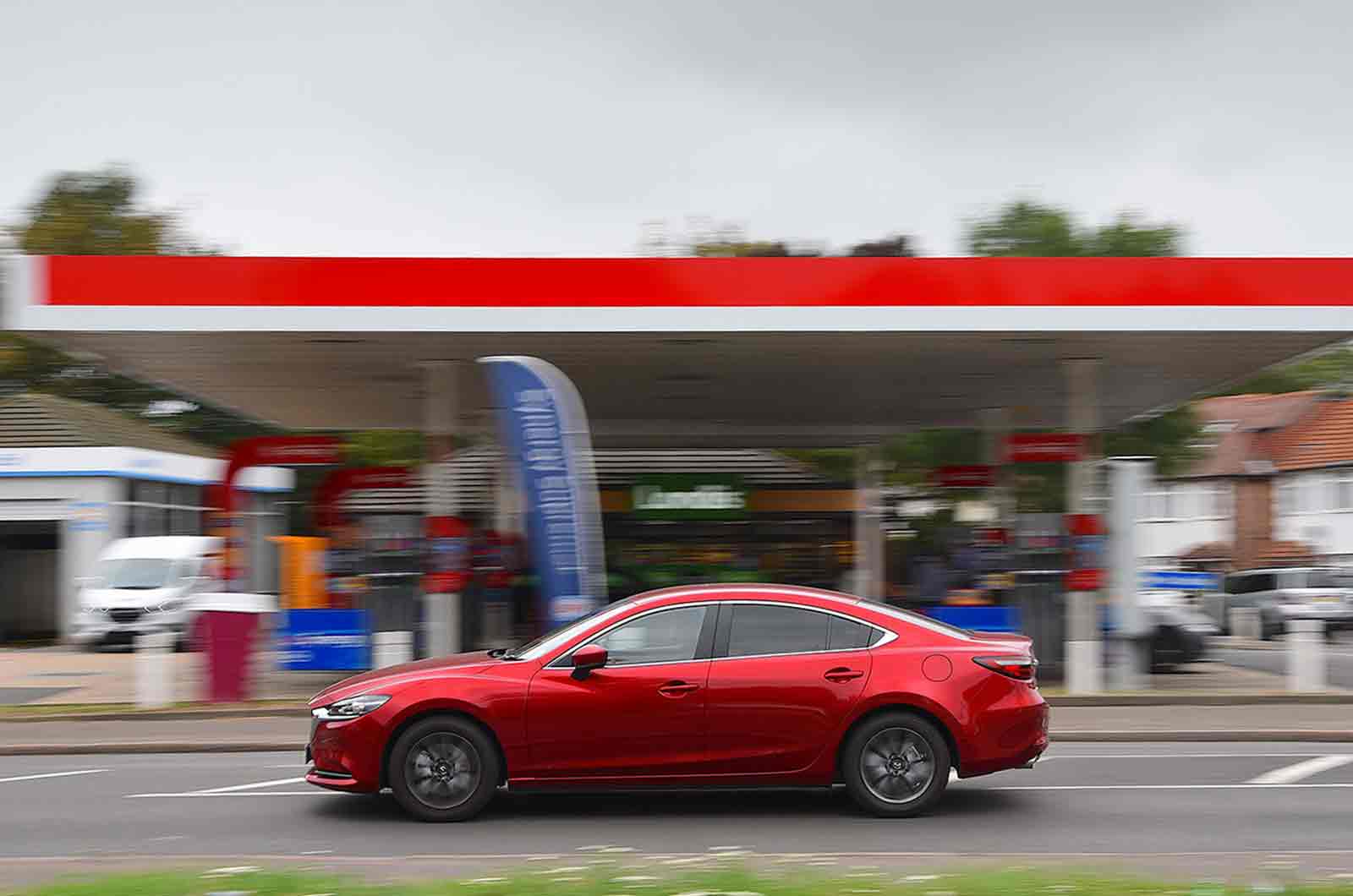 Mazda 6 driving past a petrol station
