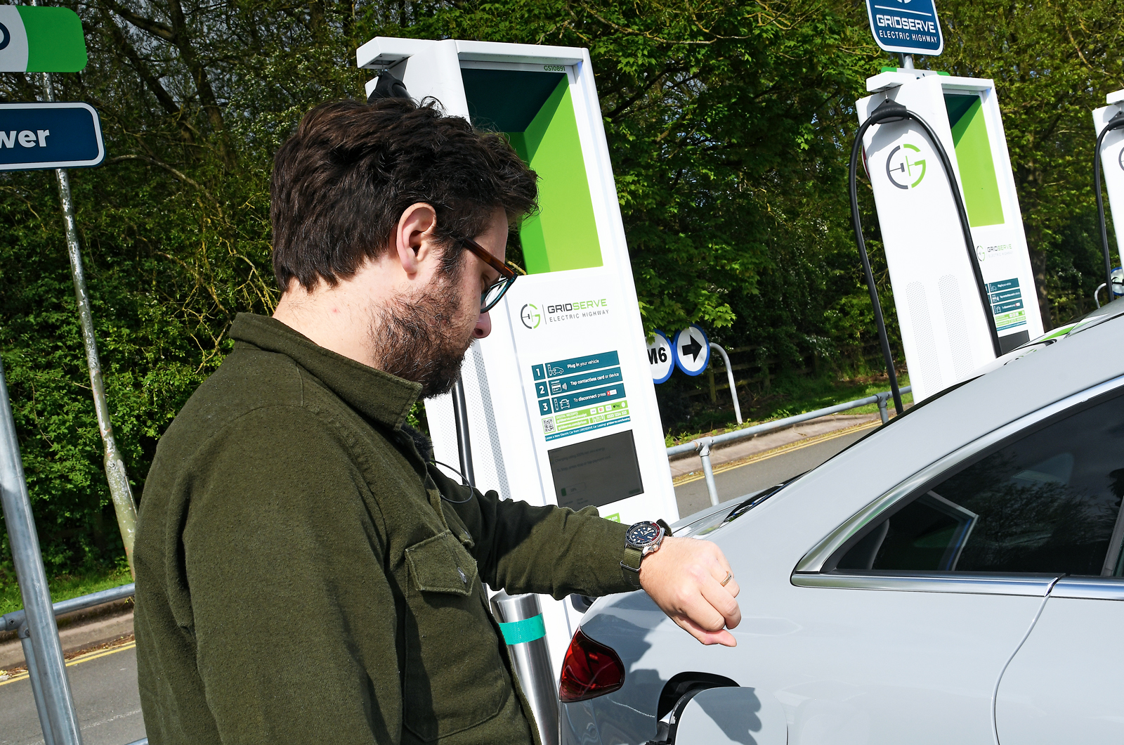 Person waiting for electric car to charge at motorway services