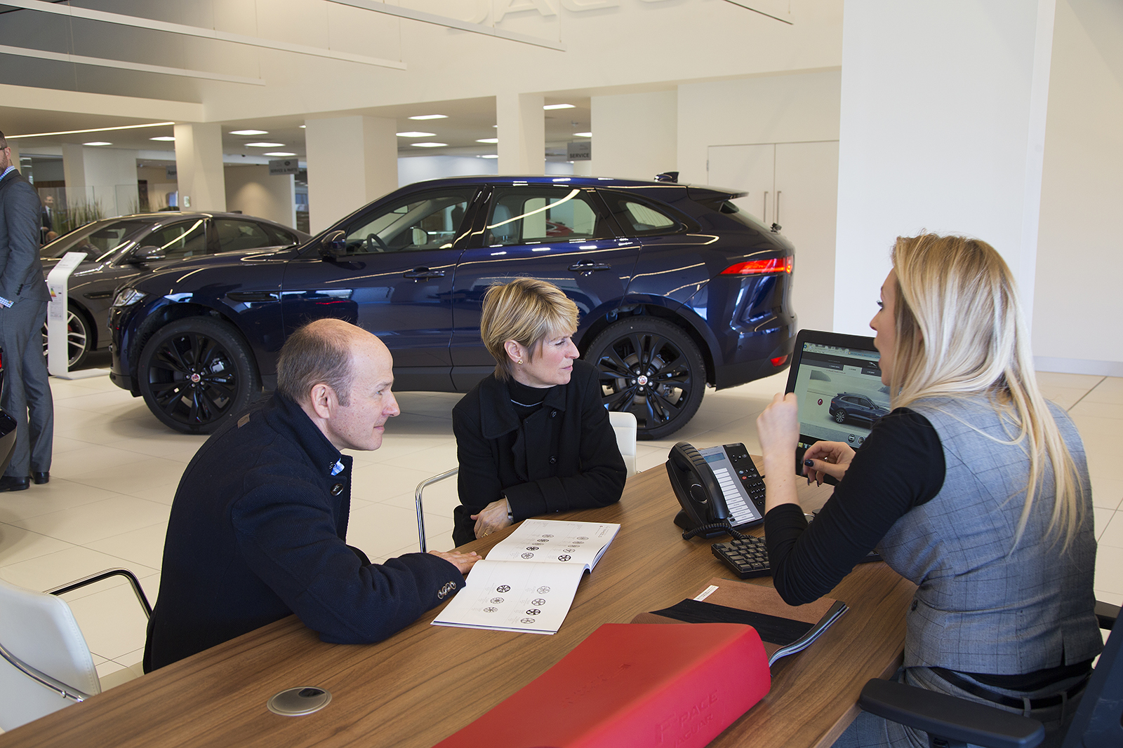 A couple talk to a car dealership employee