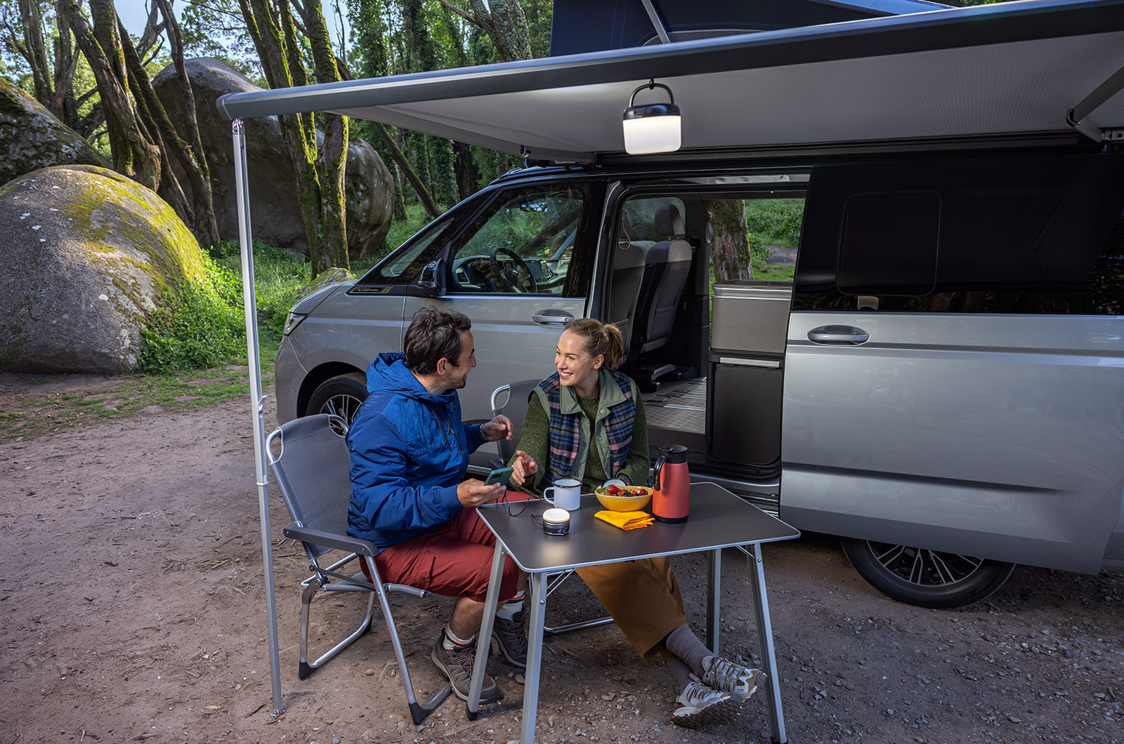 Couple sitting at a table under an awning outside of the new Volkswagen California