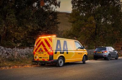 A yellow AA van pulls over behind a broken down car