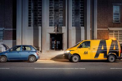An AA van arrives behind a broken down car with the bonnet up