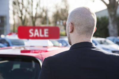 Back of a driver looking for new and used cars for sale at a dealership
