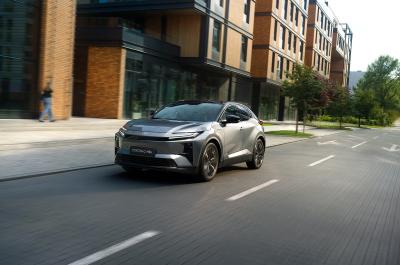 Grey Toyota C-HR+ driving through the city viewed from the front