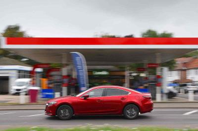 Mazda 6 driving past a petrol station