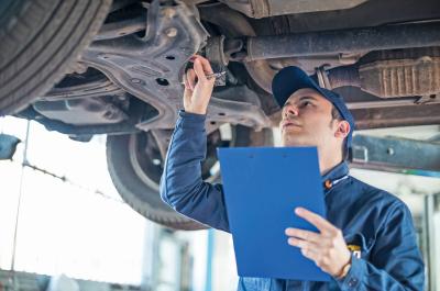 MOT inspector looks for rust underneath a car