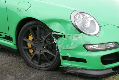 The front wing of a green Porsche 911 with crash damage