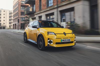 A Pop Yellow Renault 5 driving through the city viewed from the front three quarter