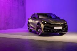 Front three-quarter static exterior shot of a grey CUPRA Tavascan in a studio with purple background lighting
