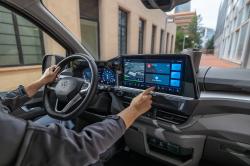 An interior shot of the Volkswagen Transporter dash area with the driver touching the infotainment screen