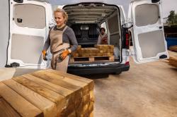 A worker loads lengths of timber into the back of a Volkswagen Transporter