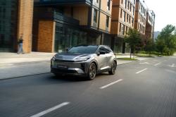 Grey Toyota C-HR+ driving through the city viewed from the front