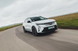 White Renault Scenic E-Tech electric driving on a country road viewed the front three-quarter