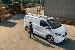 A white Volkswagen Transporter is parked next to some piles of timber
