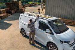 A man places some lengths of timber on the roof of the Volkswagen Transporter
