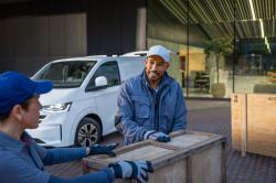 Two workers speak in front of a white Volkswagen Transporter
