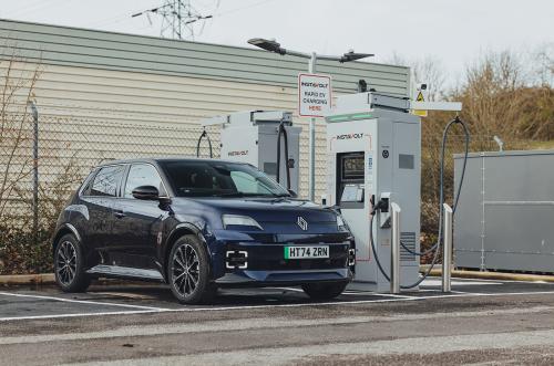 A dark blue Renault 5 E-Tech electric charging at a public charger